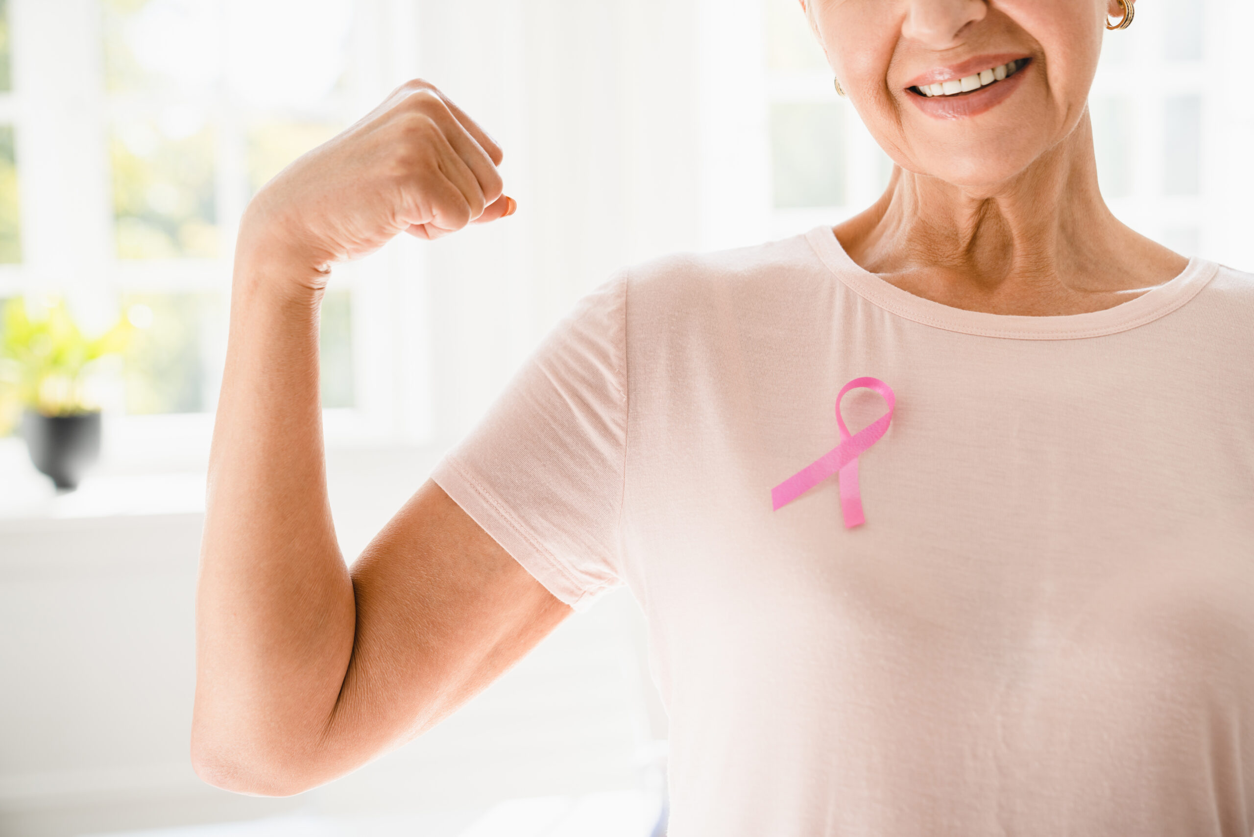 Mature senior elderly strong woman in pink t-shirt with pink ribbon supporting fighting for breast cancer movement. Togetherness, oncology recovery concept