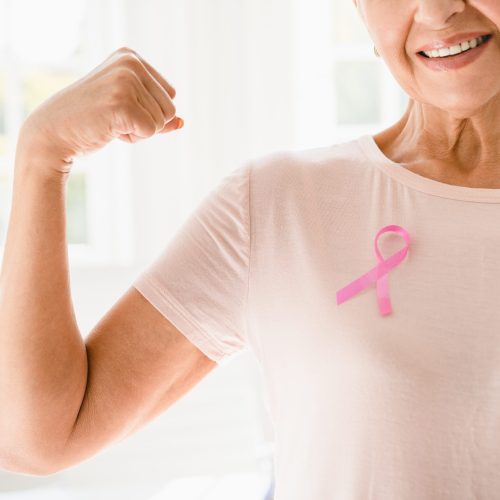 Mature senior elderly strong woman in pink t-shirt with pink ribbon supporting fighting for breast cancer movement. Togetherness, oncology recovery concept